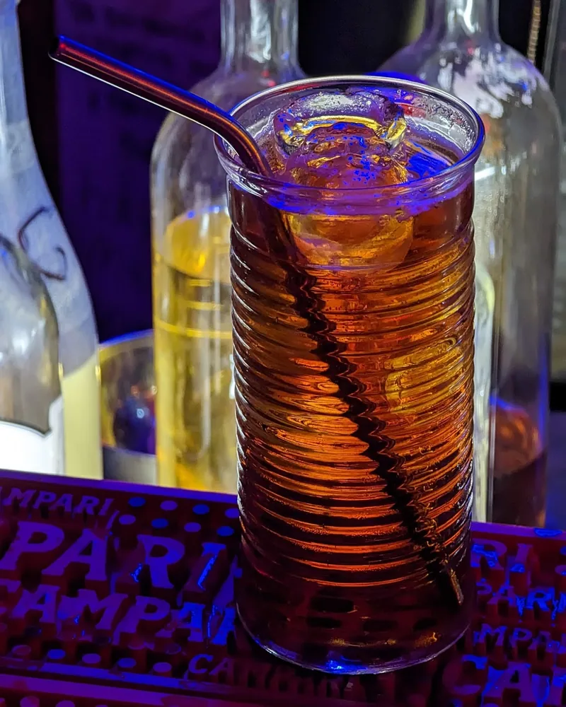 Amber cocktail in a textured highball glass with a metal straw at Ploho Bar