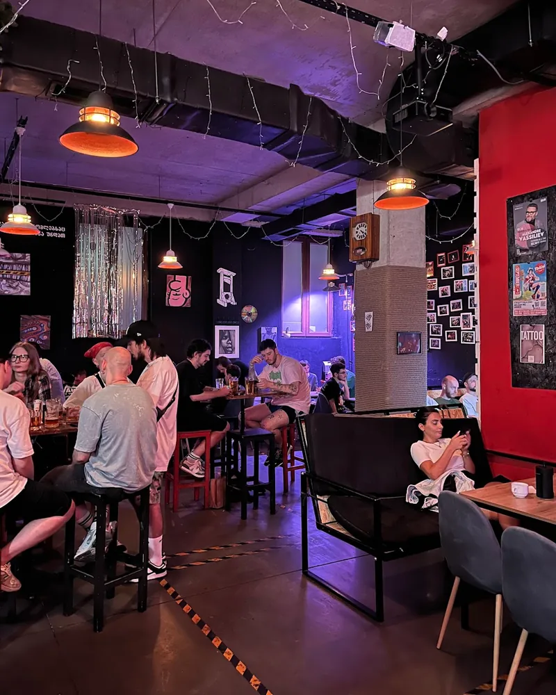 Bar seating area with hanging lamps and purple lighting at Poddon Bar