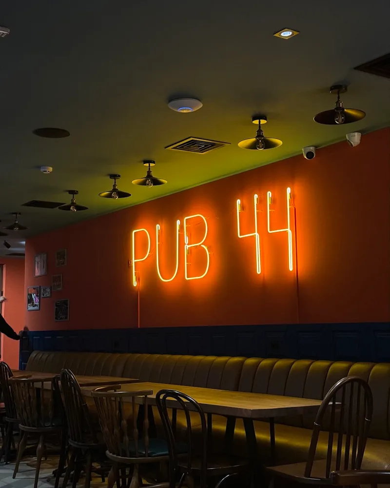 Dining area with neon pub 44 sign and booth seating at Pub 44