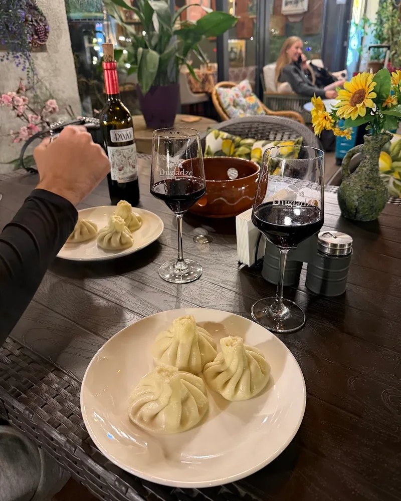 Khinkali dumplings on a plate with red wine at Ranina
