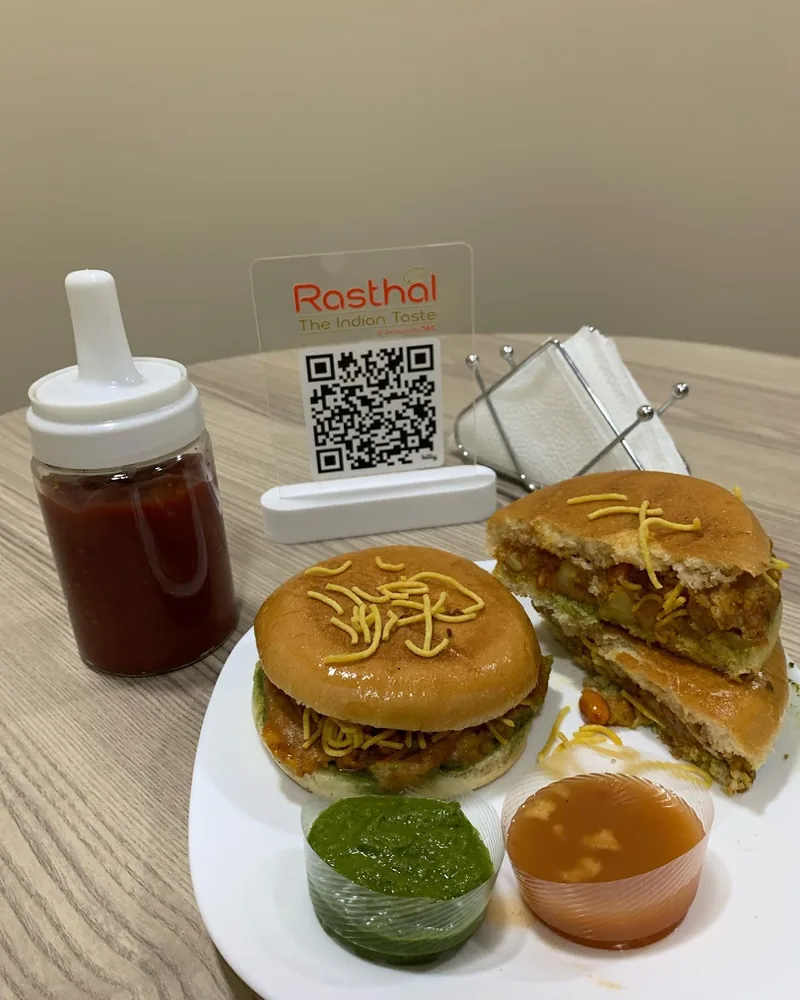 Dabeli on a white plate with chutneys at Rasthal