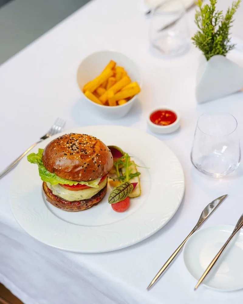 Burger with fries and dip on a white tablecloth at Reserve