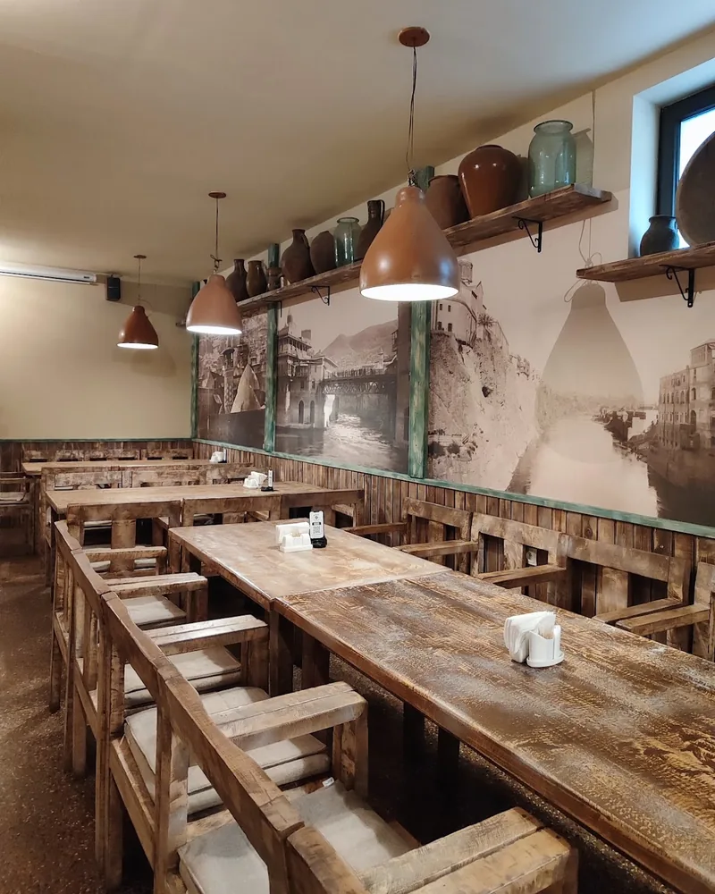 Wooden dining tables with rustic chairs and vintage photo wall at Pasanauri (Kazbegi Avenue)