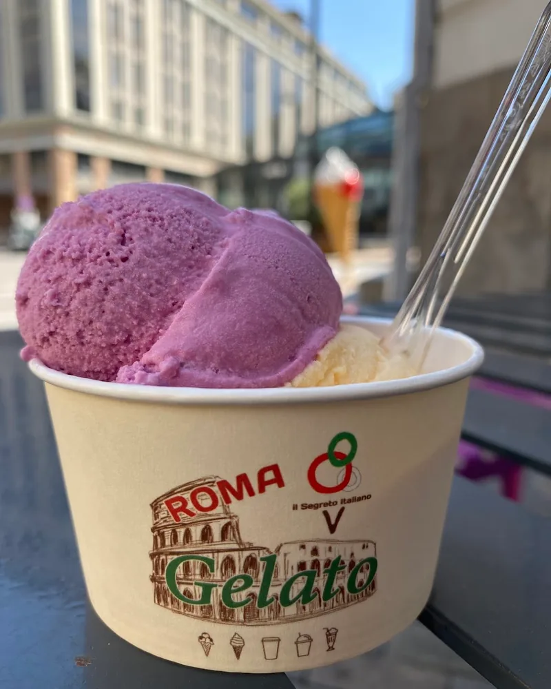 Gelato in a branded paper cup with a plastic spoon at Roma Gelato