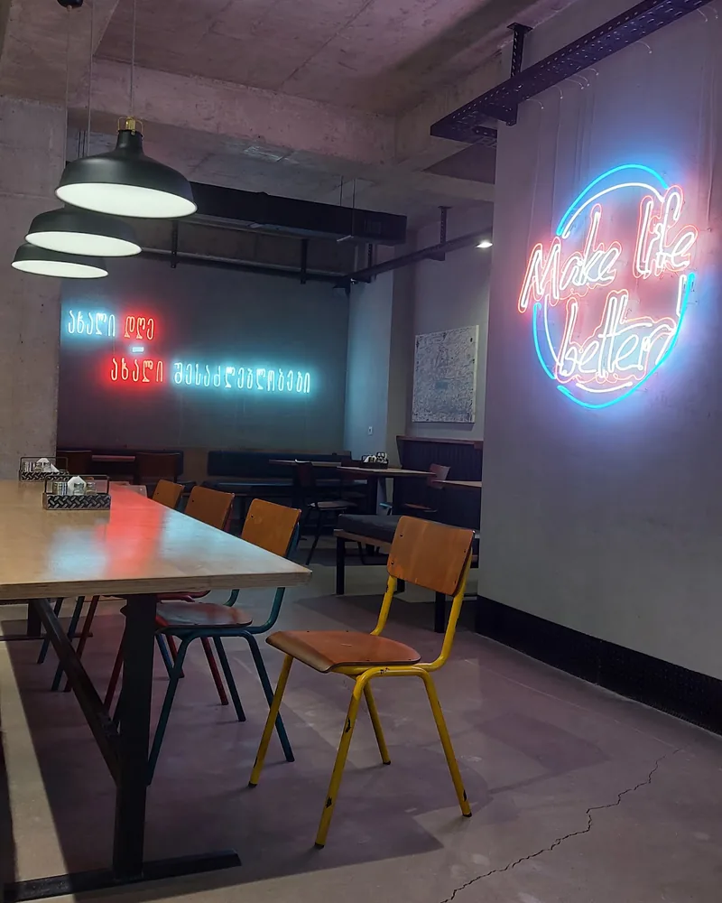 Dining area with neon signs and concrete ceiling at Ronny's Pizza (Dighomi)