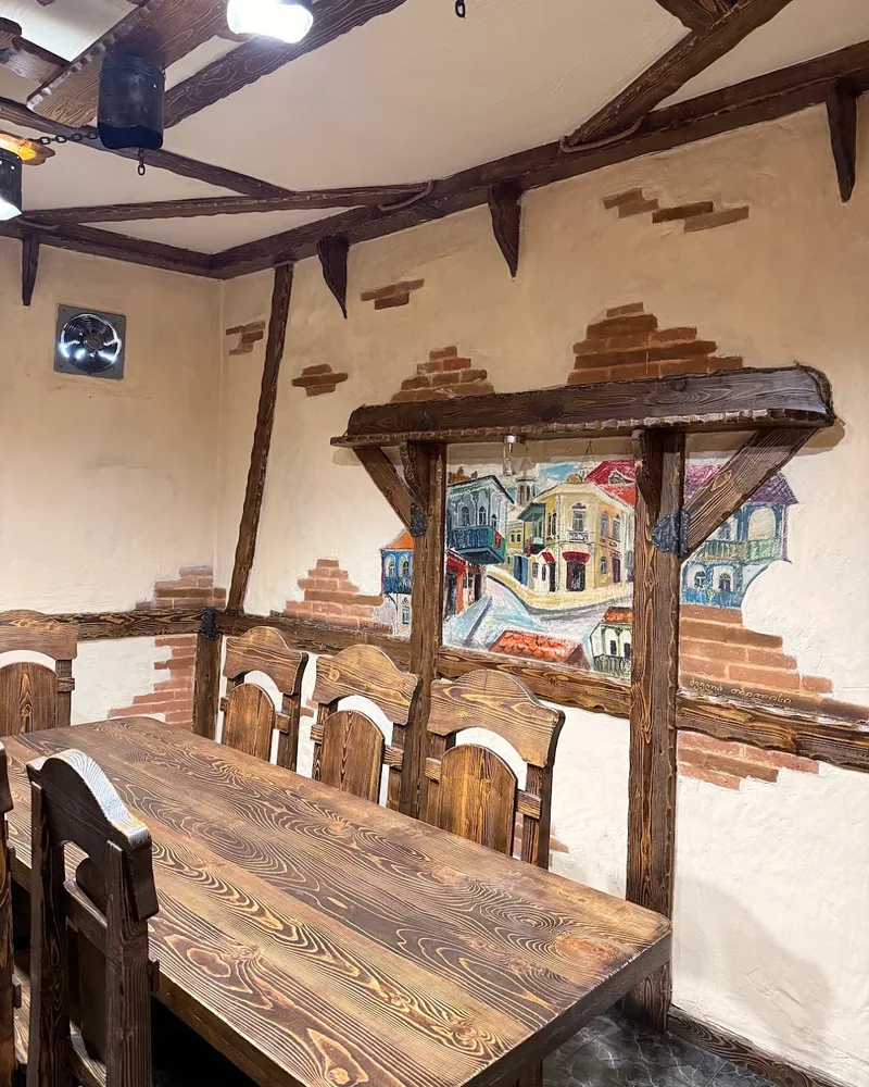 Wooden dining table and rustic chairs with painted wall mural at Royal Kitchen in Isani