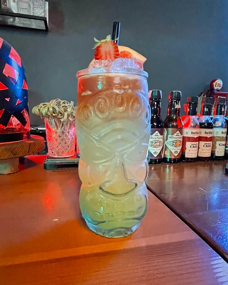 Cocktail in a tiki glass garnished with strawberry and grapefruit at Rudeboy Bar