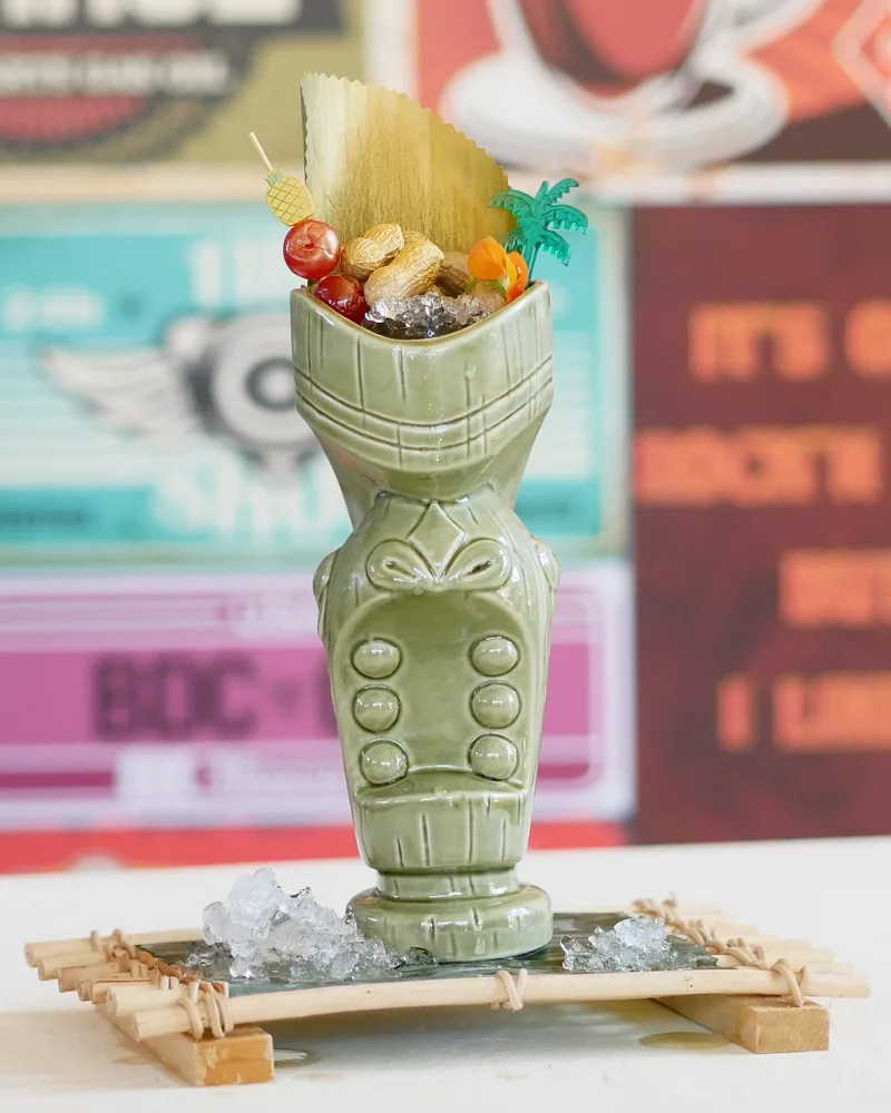 Tiki cocktail in a ceramic tiki mug with crushed ice and garnishes at Rum Roof Kitchen Bar