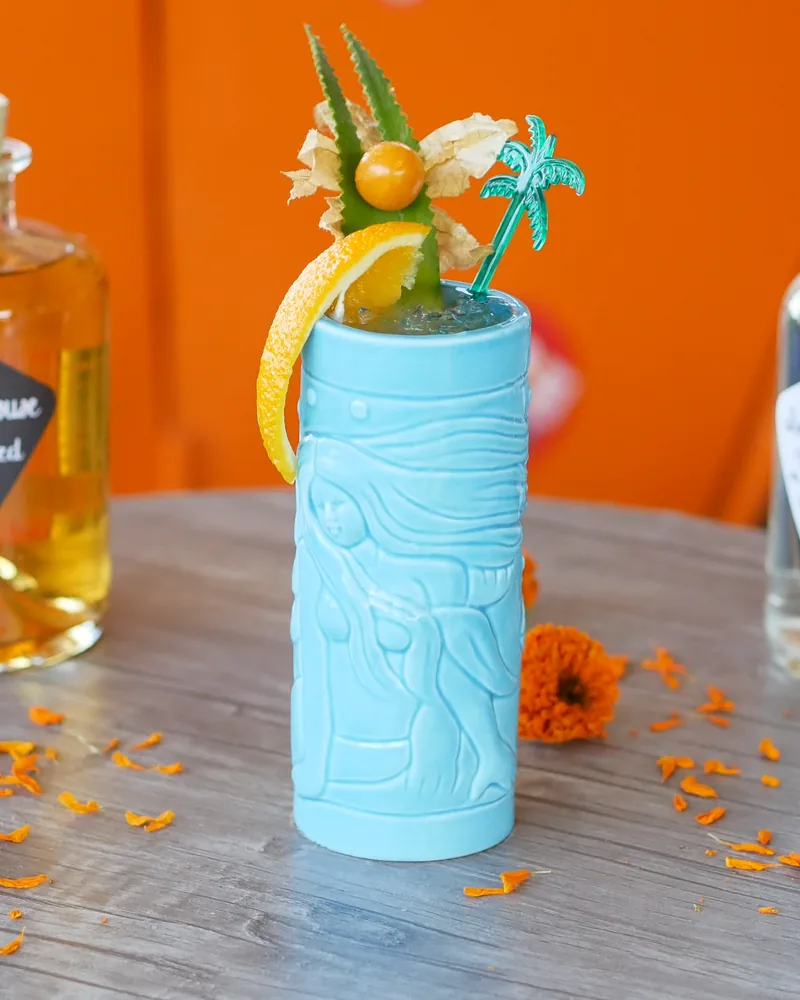 Tiki cocktail in a blue ceramic mug with citrus and a palm tree garnish at Rum Roof Kitchen Bar