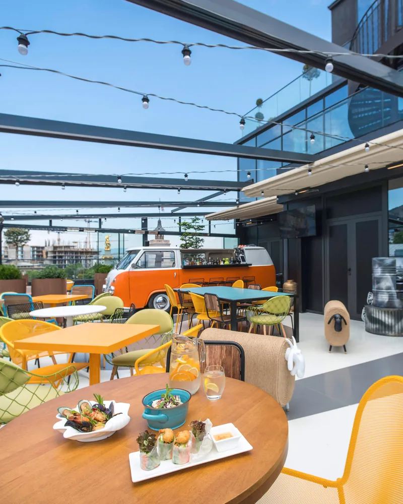 Rooftop terrace with colourful chairs and an orange van bar at Rum Roof Kitchen Bar