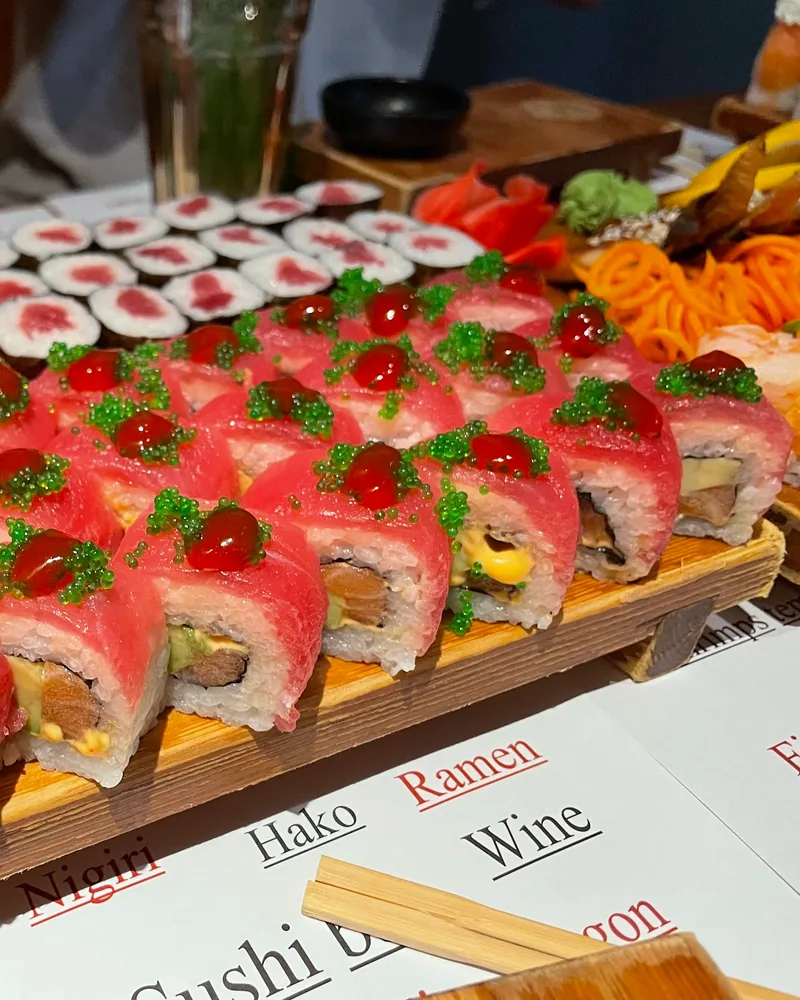Sushi rolls topped with tuna and tobiko on a wooden board at Saikou Sushi Bar