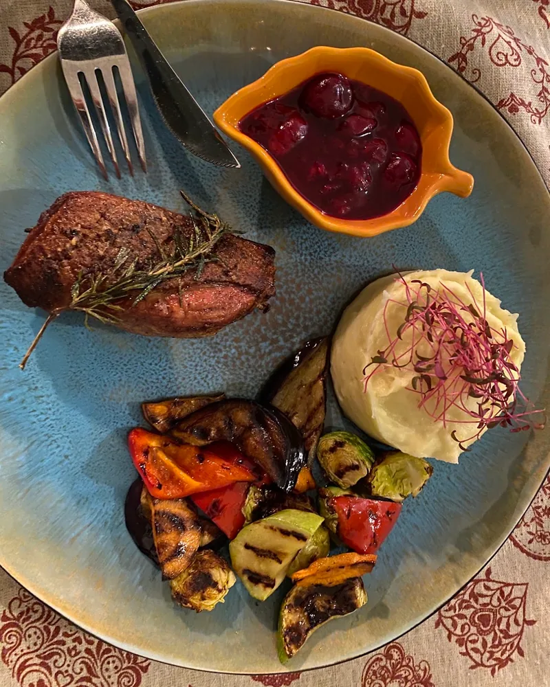Seared meat with grilled vegetables, mashed potatoes and berry sauce at Sakhli Kipianze