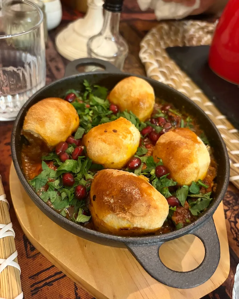 Georgian stew topped with baked bread buns and pomegranate seeds at Sakhli Kipianze