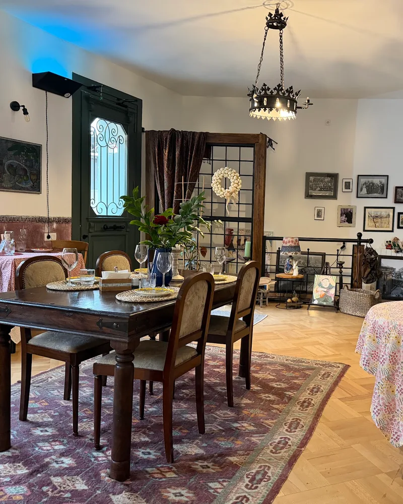 Dining room with wooden tables, patterned rugs and vintage decor at Sakhli Kipianze