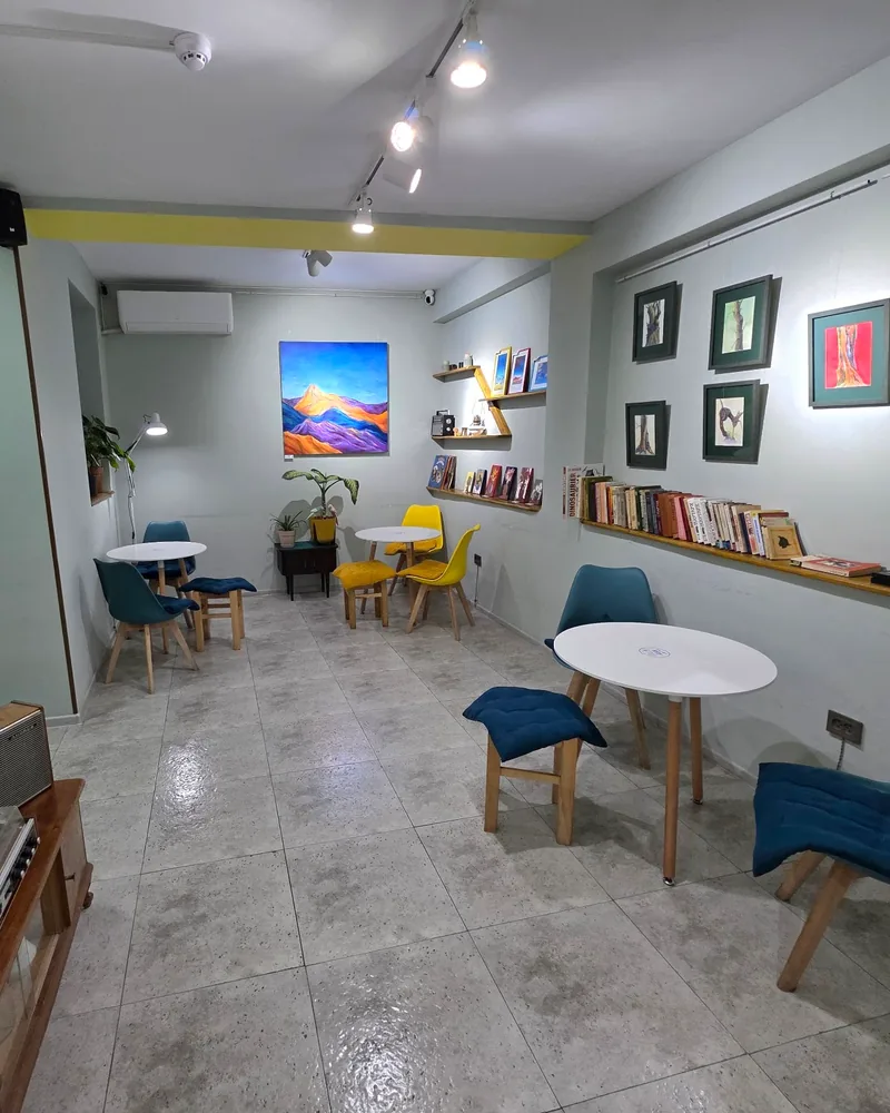 Seating area with artwork and small tables at Sali Coffee