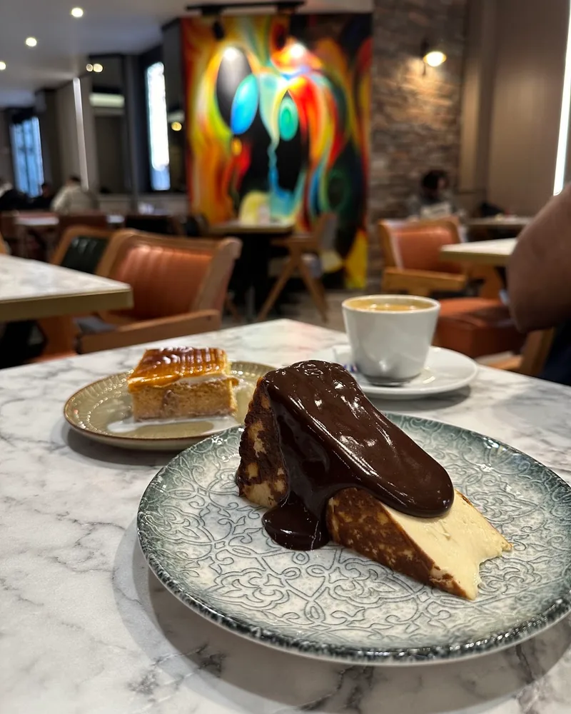 Cheesecake with chocolate sauce on patterned plate at Sapore Cafe