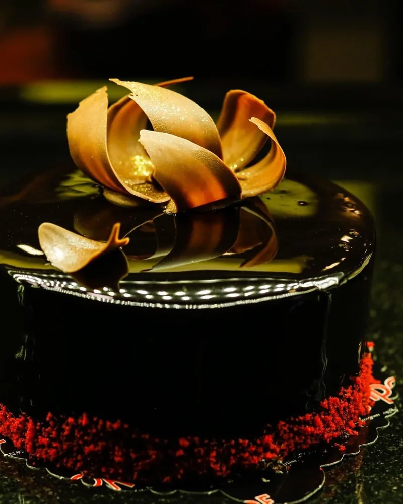 Glossy chocolate mirror glaze cake with chocolate garnish at Sapore Cafe