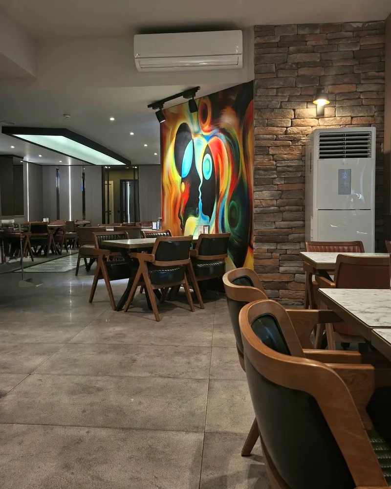 Cafe dining area with abstract mural and brick wall at Sapore Cafe