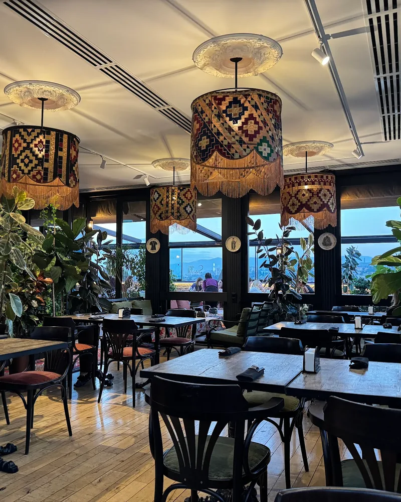 Dining room with patterned pendant lamps and potted plants at See360