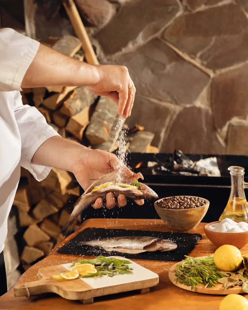 Chef seasoning raw trout with salt at Sharbati
