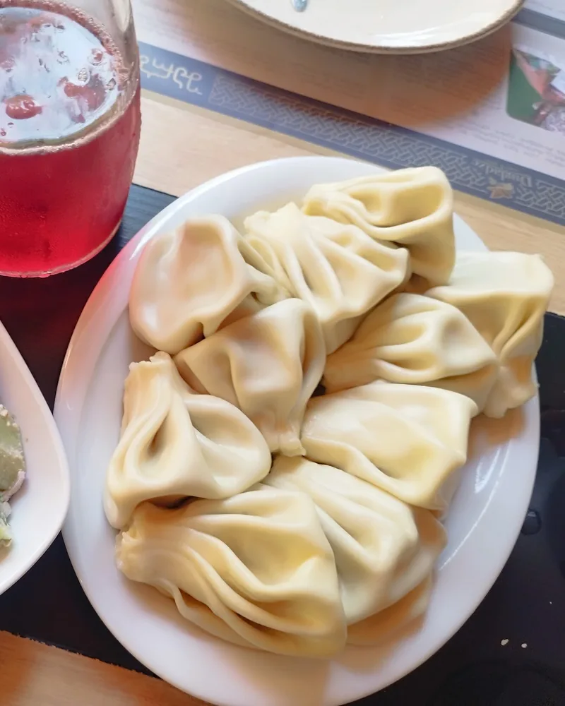 Khinkali dumplings with cucumber salad and compote drink at Sharbati