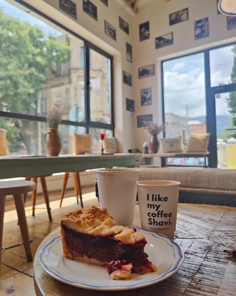 Berry pie slice on a plate with takeaway coffee cups at Shavi Coffee Roasters