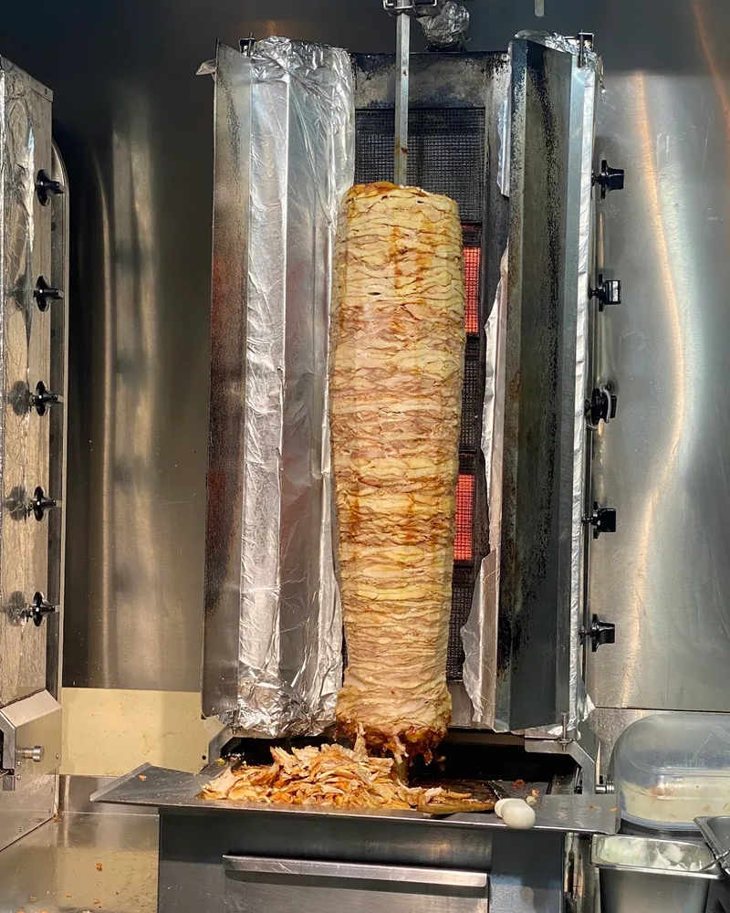 Shawarma rotating spit with sliced chicken at Shawarma Haifa