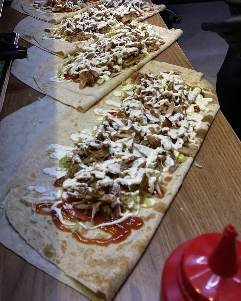 Shawarma wraps being assembled on flatbreads at Shawarmaniac