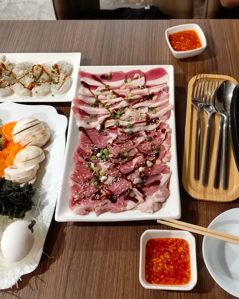 Thai mookata barbecue table setup with sliced meats and vegetables at Siam Thai Cuisine
