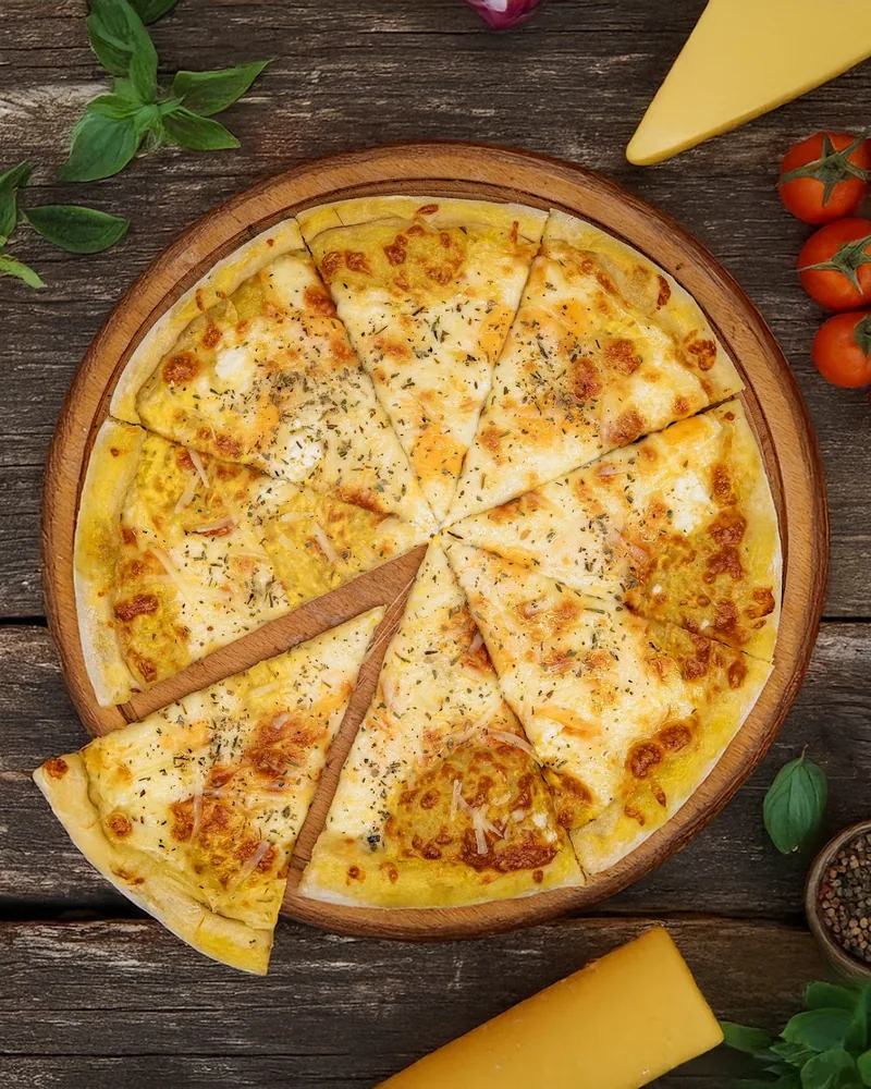 Four cheese pizza sliced on a wooden board at Silo's Pizza & More