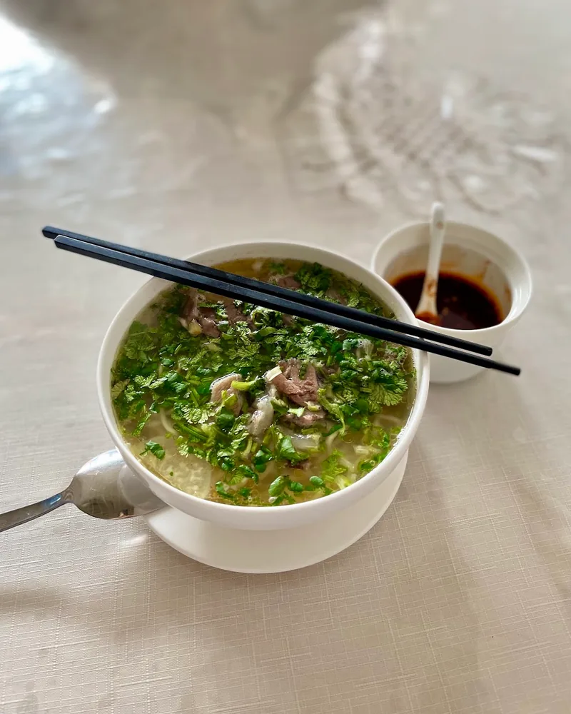 Beef noodle soup topped with coriander at Taste of Xinjiang