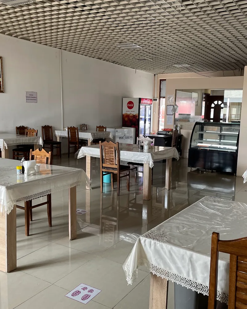 Dining room with wooden chairs and white tablecloths at Taste of Xinjiang