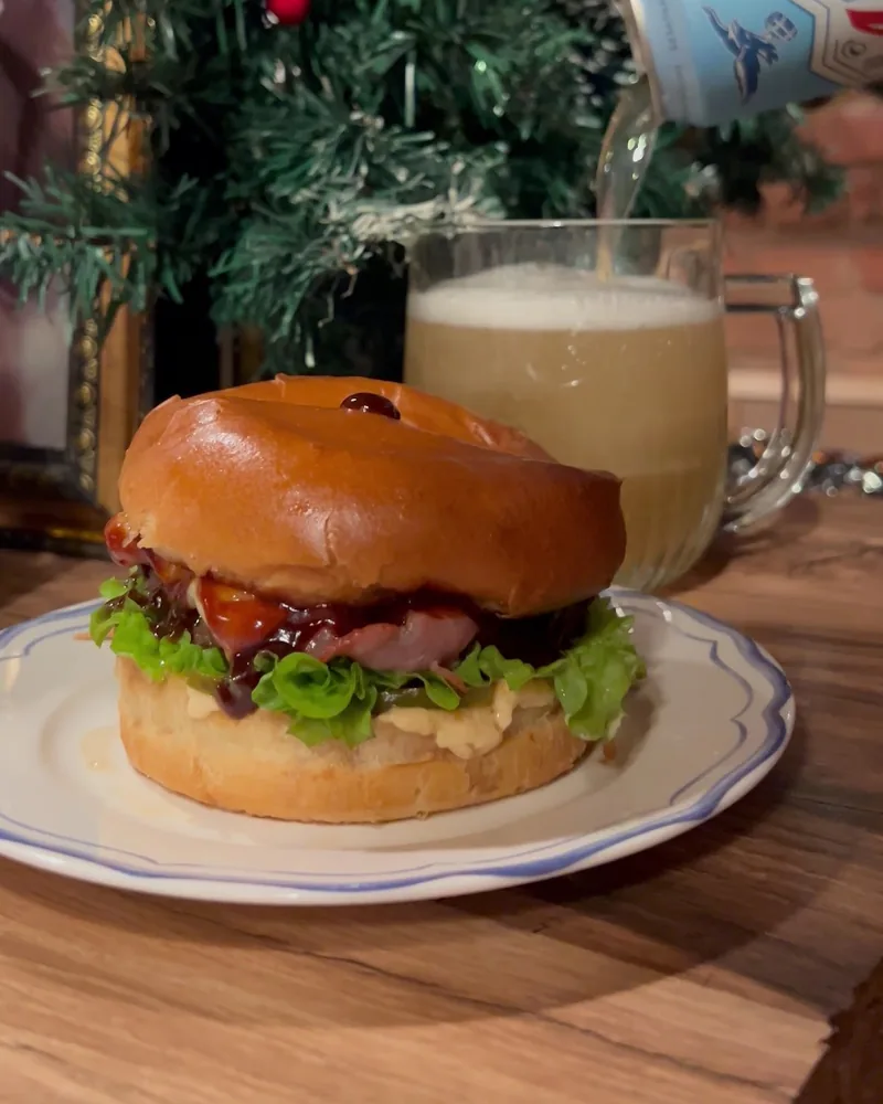 Burger with lettuce and sauce on a plate with beer poured into a mug at Sma - Craft Beer Bar