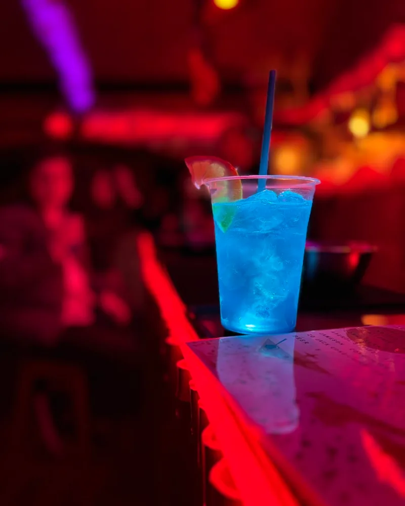 Bright blue cocktail in a plastic cup with an orange slice at Snappy Bar
