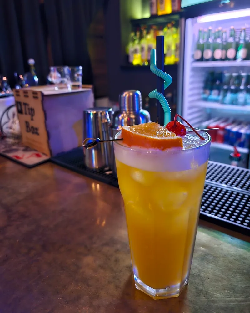 Yellow cocktail with orange slice and cherry at Sonder Bar