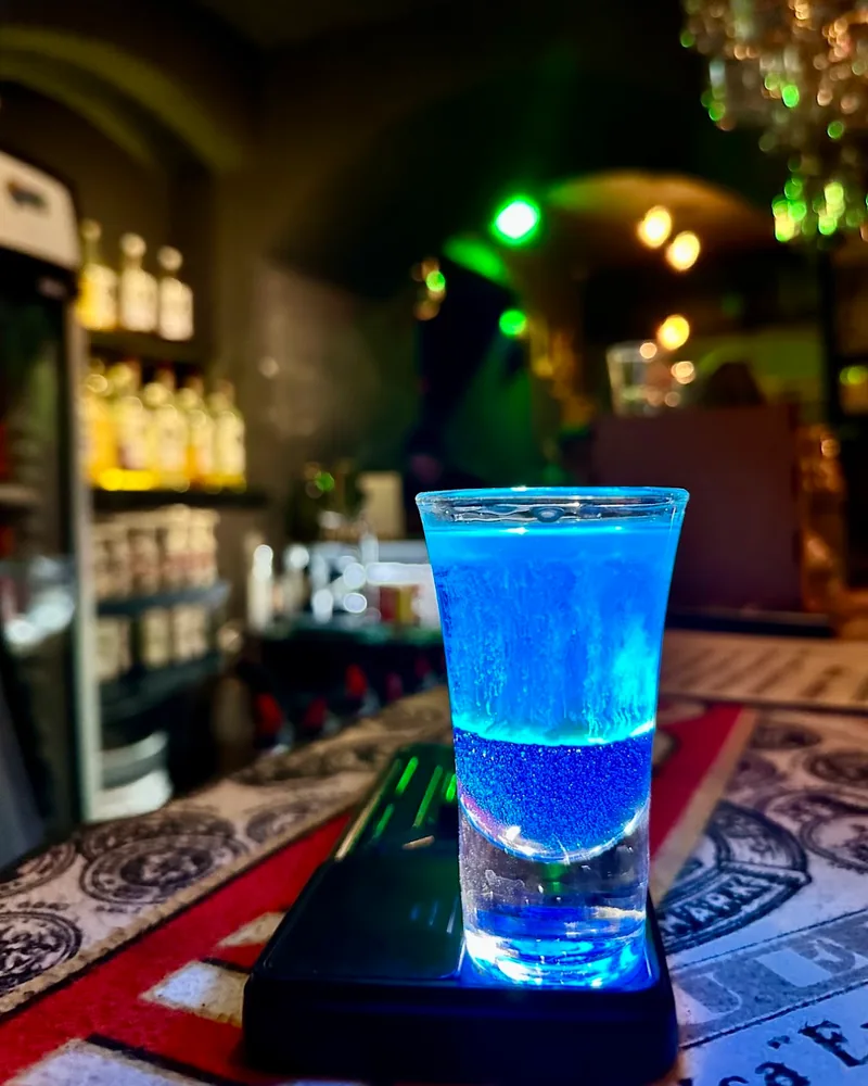Blue layered shot in a shot glass on a lit coaster at Sonder Bar