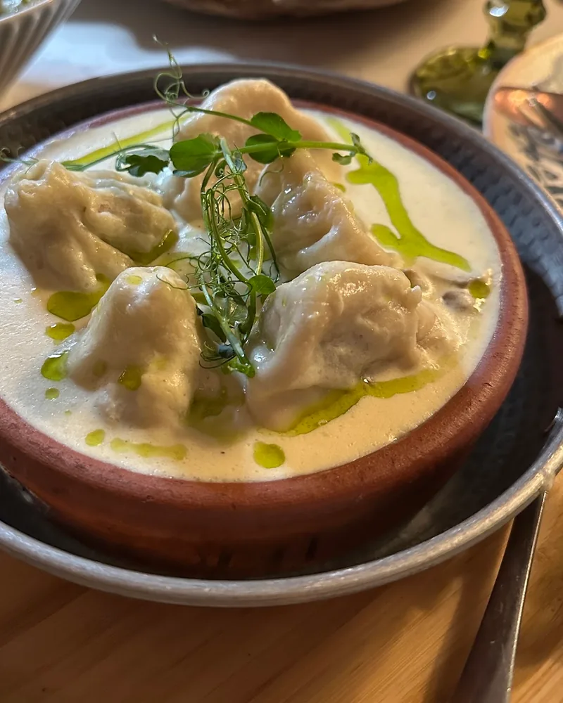 Khinkali in creamy garlic sauce in a clay bowl at Sormoni