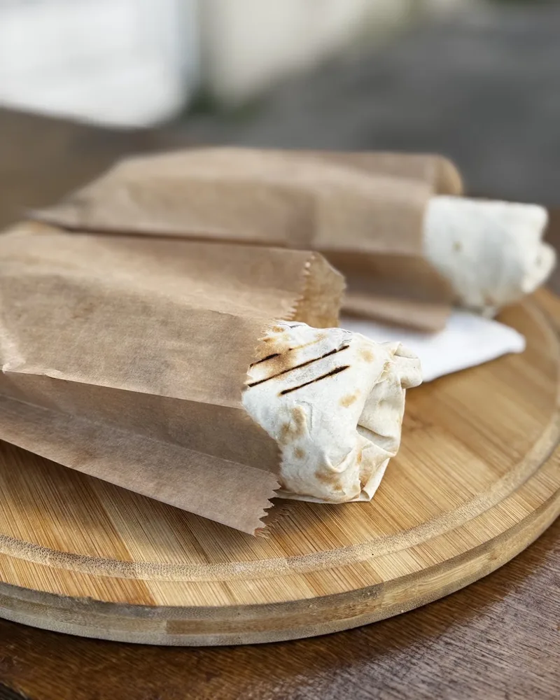 Wrapped shawarmas in paper sleeves on a wooden board at Soul Shaurma