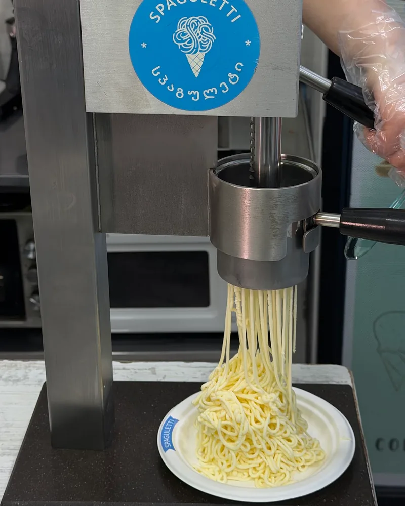 Spaghetti ice cream being extruded onto a paper plate at Spaguletti Ice Cream & Waffles