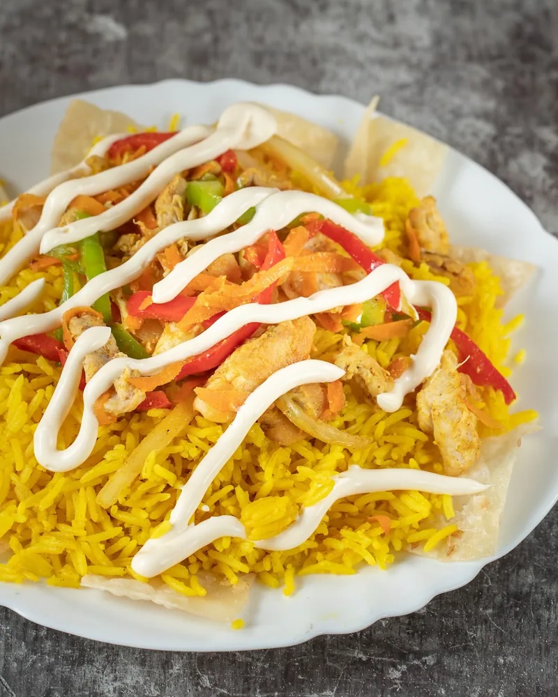 Yellow rice with chicken, vegetables, and white sauce at Spectra