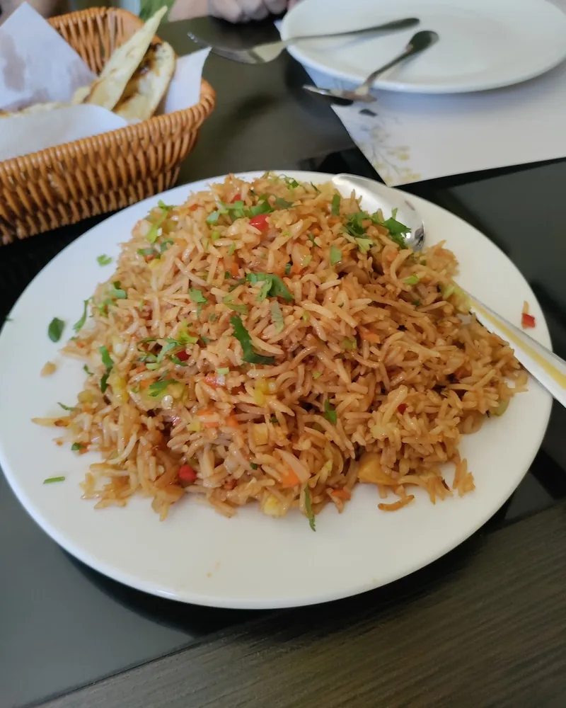 Fried rice on a white plate with a spoon at Spice Garden