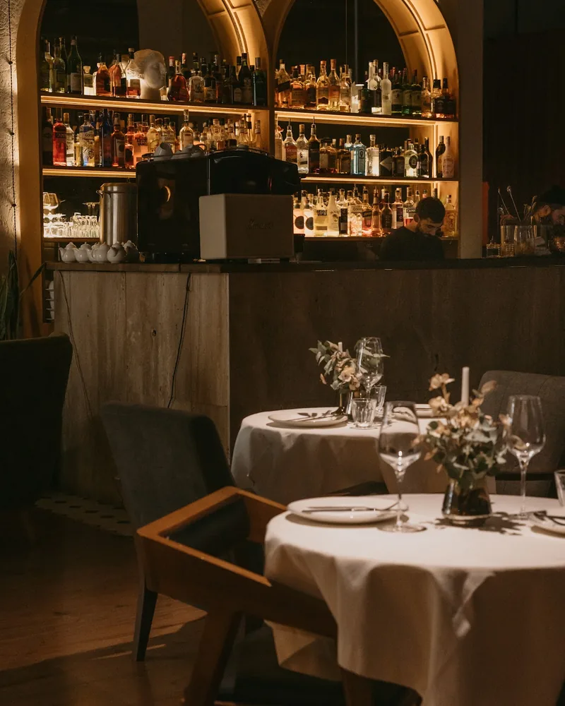 Dining tables with backlit arched bar shelves in background at St.Bunny