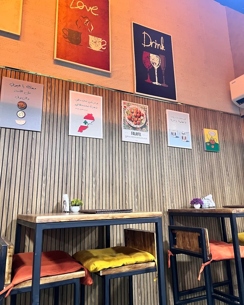 Wooden slat wall and seating area with framed posters at Station 1984