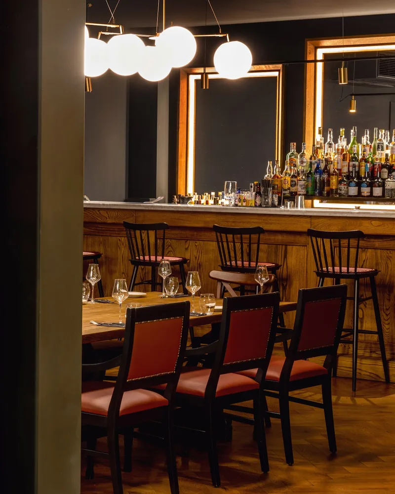 Dining table and bar counter framed by wine rack at Steakhouse by Gastronome