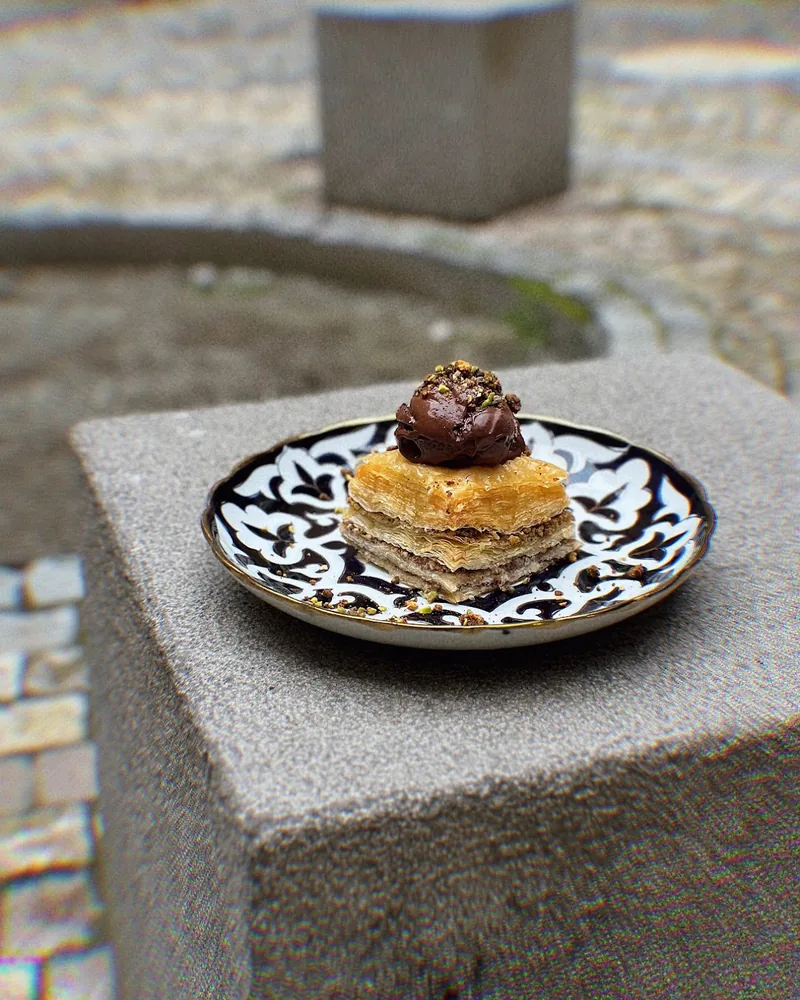 Baklava topped with a scoop of chocolate on a patterned plate at Stricha