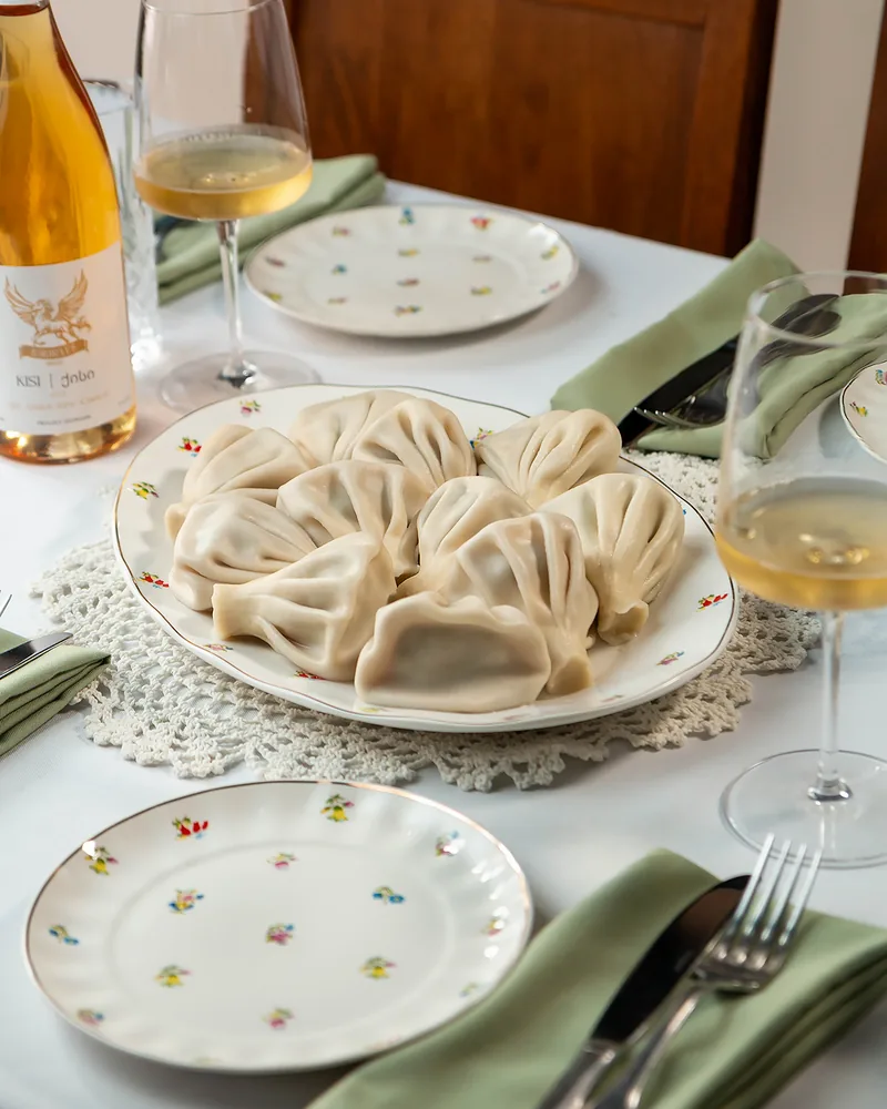 Khinkali on an oval platter with white wine at Stumari