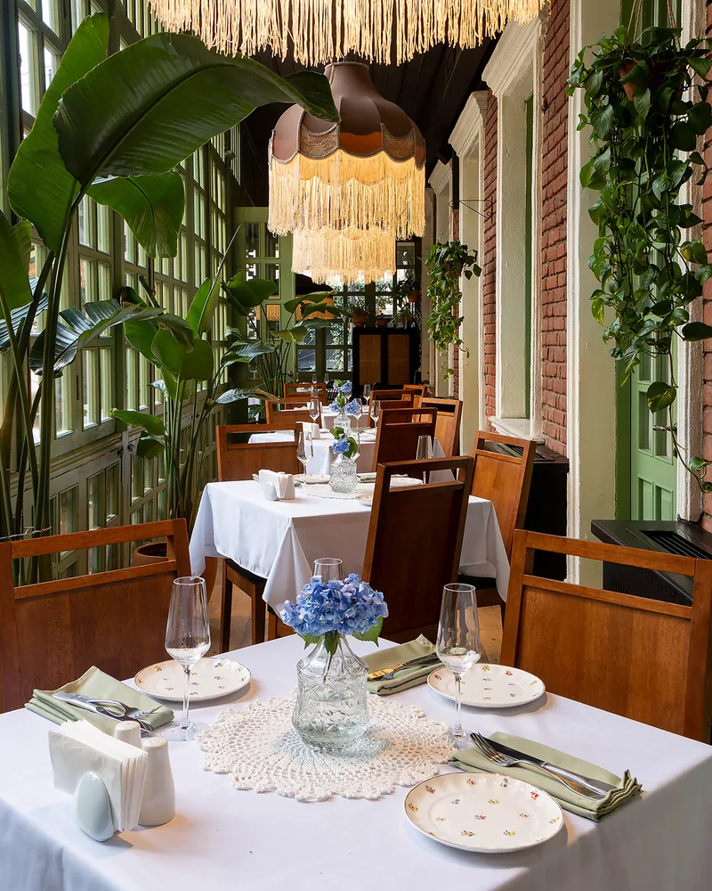 Enclosed veranda dining area with fringed lampshades and plants at Stumari