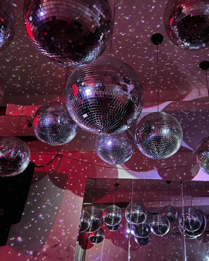 Disco balls hanging from the ceiling with light reflections at Success Bar