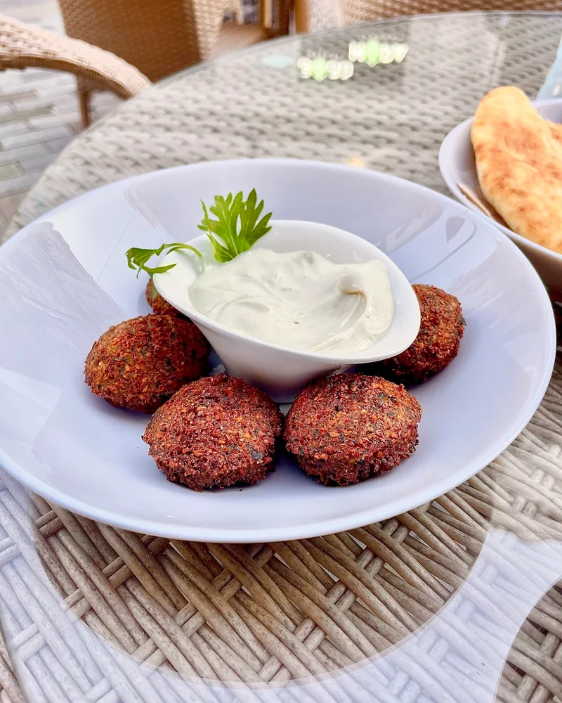 Falafel with white dipping sauce in a bowl at Supra Hummus