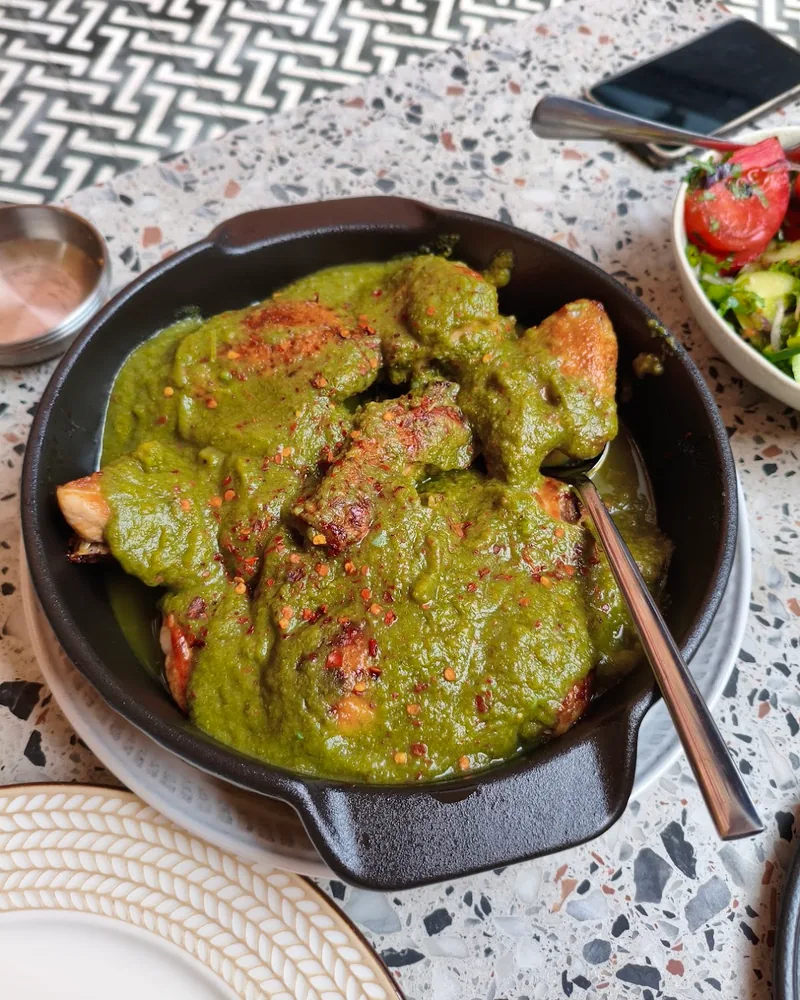 Chicken in green sauce in a cast iron pan at Supra Sololakshi